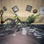 Green mechanical mantis model with vintage newspaper background
