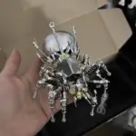 Metallic spider robot model held in hand